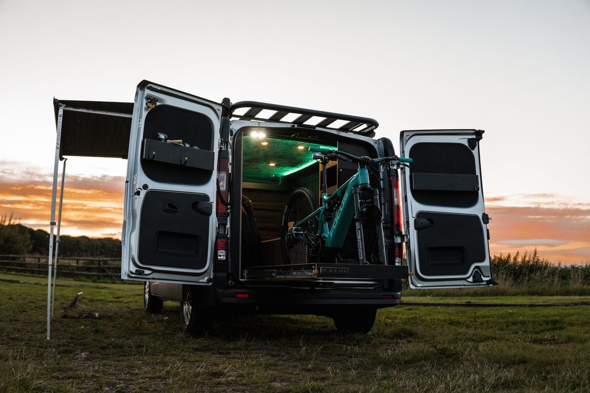The Ride Companion s converted Nissan Primastar parked on the field with the back doors open to reveal the van interior containing a bike Nissan teams up with The Ride Companion to create mobile Primastar podcast studio