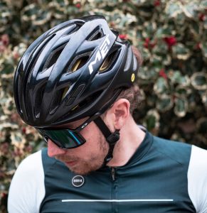 Met helmet on road rider paused at roadside with hedge behind him